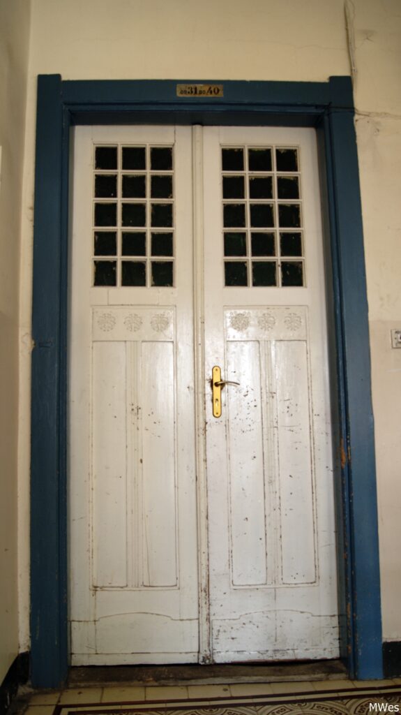 Przeszklenie drzwi z klatki schodowej oficyny poprzecznej, na korytarz prowadzący do mniejszych mieszkań. Fot. Monika Wesołowska, 2020, źródło: lapidarium detalu.