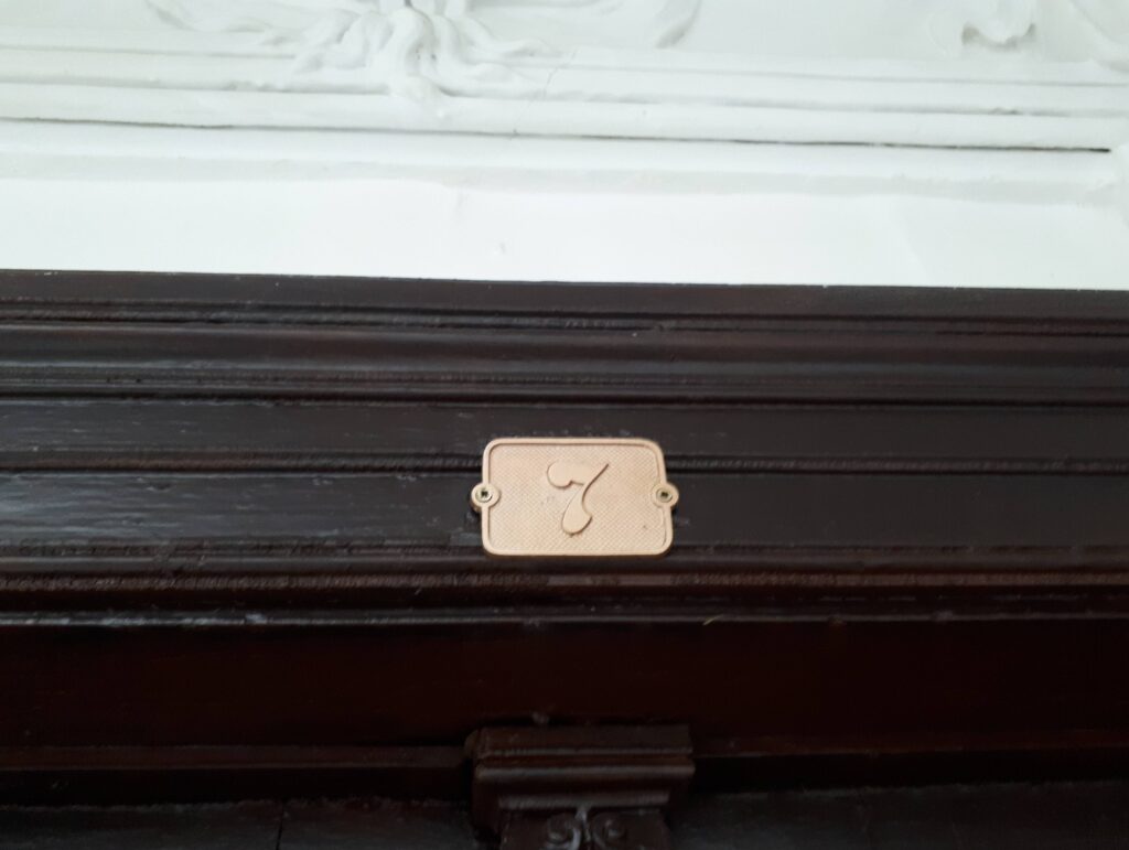 Numer na drzwiach do mieszkania na klatce schodowej od strony ulicy Mokotowskiej. Fot. Robert Marcinkowski, 2020, źródło: lapidarium detalu.