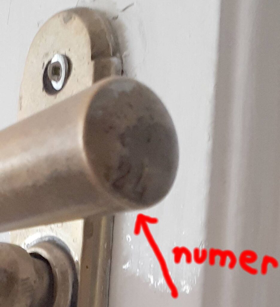 Numer na klamce w drzwiach w mieszkaniu głównej klatki schodowej. Fot. Robert Marcinkowski, 2020, źródło: lapidarium detalu.