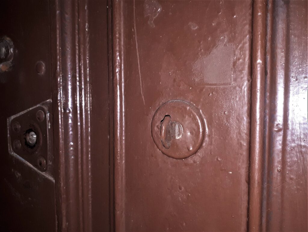 Zamalowany dzwonek na drzwiach do mieszkania, klatka schodowa w oficynie zach. Fot. Robert Marcinkowski, 2020, źródło: lapidarium detalu.
