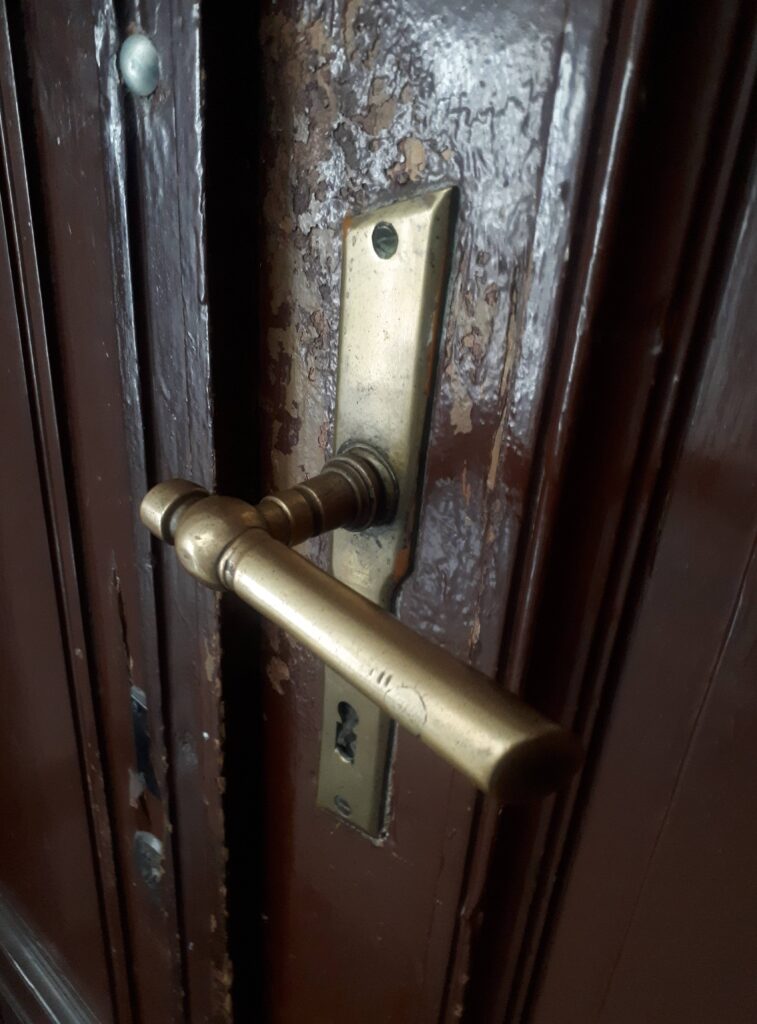 Klamka u drzwi do mieszkania, klatka schodowa w oficynie płn. Fot. Robert Marcinkowski, 2020, źródło: lapidarium detalu.