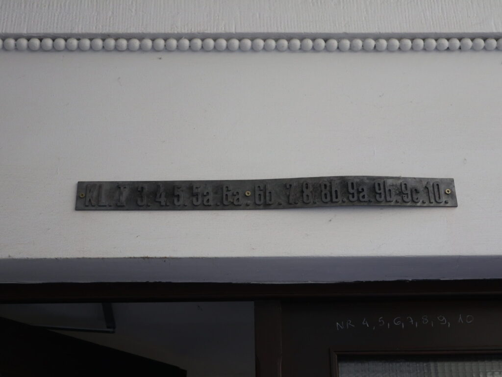Tabliczka z numerami mieszkań nad wejściem do głównej klatki schodowej. Fot. Cecylia Rotter, 2020, źródło: lapidarium detalu.