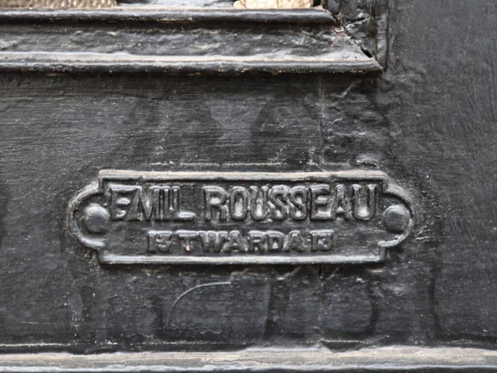 Tabliczka firmowa producenta wrót bramy, firmy Emil Rousseau Twarda 13, brama w elewacji frontowej. Fot. Cecylia Rotter, 2020, źródło: lapidarium detalu.