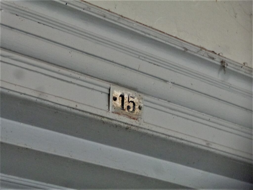 Tabliczka z numerem mieszkania, główna klatka schodowa. Fot. Robert Marcinkowski, 2019, źródło: lapidarium detalu.
