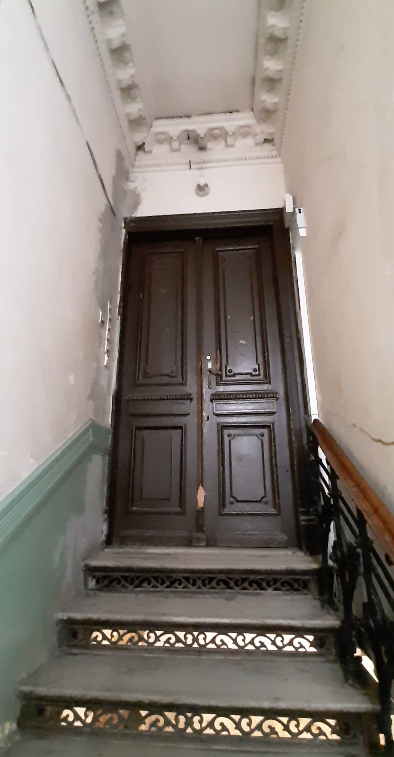 Klatka główna. Drzwi do podzielonego na 7 części mieszkania ostatniego piętra. Fot. Agnieszka Dziubiel. 2022 r., źródło: AOD III.