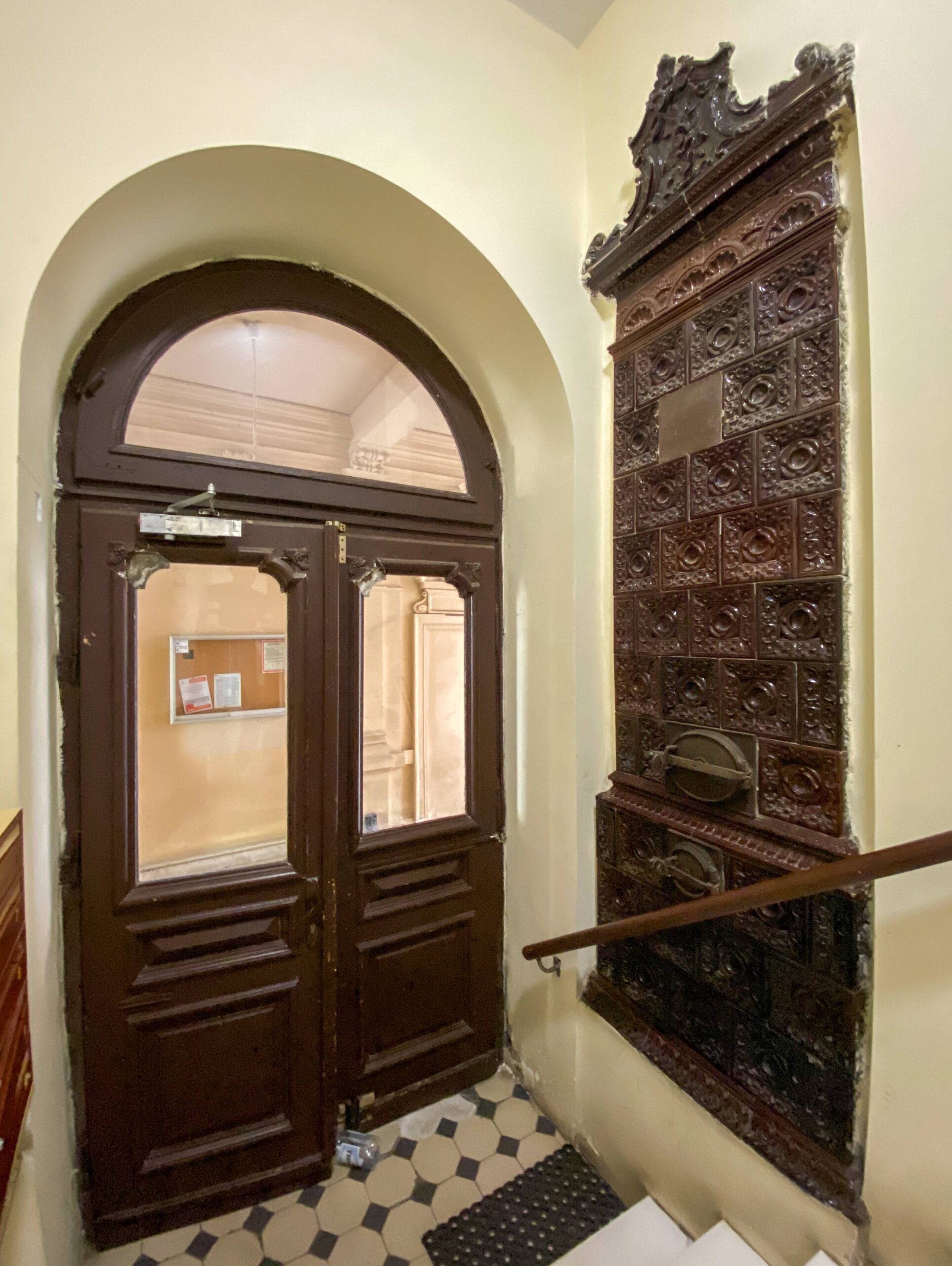 Drzwi z głównej klatki schodowej do bramy. Piec przy wejściu. Fot. Wojciech Kmieć 2022 r., źródło: AOD III.