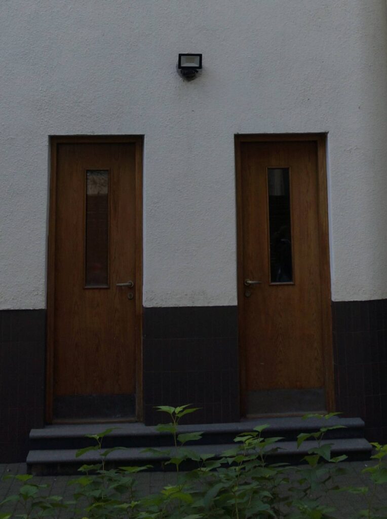 Elewacja podwórzowa. Widok na południe. Drzwi do pomieszczeń technicznych (?) pod klatką schodową. Fot. Dagmara Komorniczak , 2023 r., źródło: MWKZ.